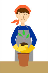 Portrait of a young woman wearing overalls planting a plant in a flower pot.
