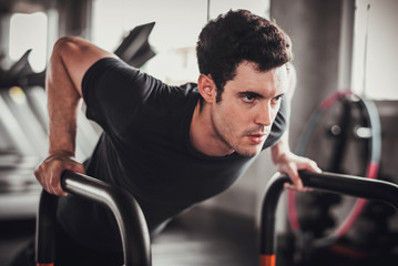 Fototapeta na wymiar Cinematic tone of young attractive fitness man exercise with machine in gym. Individual sport to training and fit muscles of body for healthy life concept. 