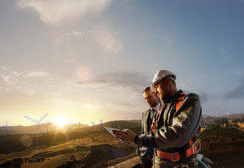 Windmill engineer and businessman planing new ecology project. they standing and looking in tablet....