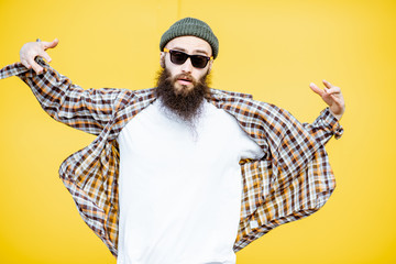 Portrait of a cool stylish man in shirt and hat posing on the bright yellow background