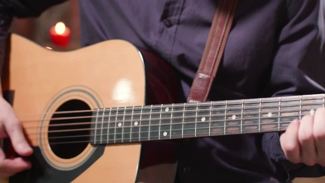 Male hands performing a rythm on an acoustic guitar. Man changes chords while playing a song.
