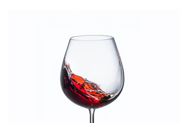 Splashing red wine in a glass on a white background
