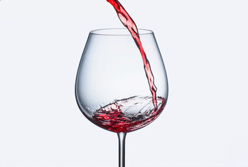 Pouring red wine in a glass with splashes
