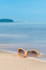 Fototapeta na wymiar Fashion sunglasses on the beach, blurry blue sea and sky background