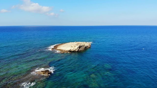 Flat rocks submerged in sea, aerial shot of Crete island cape. Beautiful nature, sea bottom seen through transparent clear waters. Vibrant seawater colour from green to blue at horizon