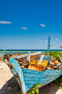 Colorful old wooden fishing boat abandoned on the Maldives beach with sea view