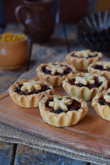 Mini Tartlets with dried fruits and nuts. Shortbread cookies with fruits stuffing on wooden background. Small sweet pie. Copy Space.