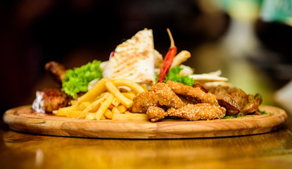 Restaurant food. Snack for beer. Wooden board with lot french fries fish sticks burrito and meat steak served with salad. Pub menu snack. High calorie snack for group friends. Tasty delicious snacks