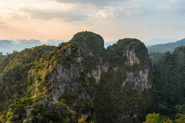 Mountain and cliffs in Thailand is covered with tropical greenery at sunset