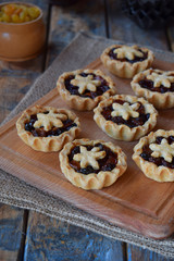 Mini Tartlets with dried fruits and nuts. Shortbread cookies with fruits stuffing on wooden background. Small sweet pie. Copy Space.