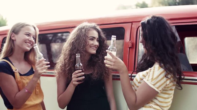 A group of friends standing outdoors on a roadtrip through countryside, clinking bottles.