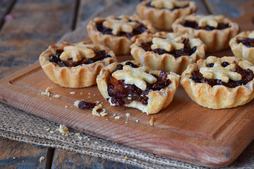 Mini Tartlets with dried fruits and nuts. Shortbread cookies with fruits stuffing on wooden background. Small sweet pie. Copy Space.