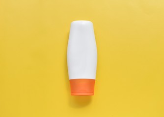 Sunscreen lotion bottle mock up on bright yellow background, skin protection from sun concept.