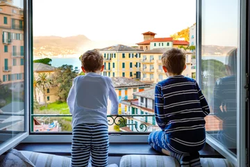 Poster Im Rahmen Two little kids boys enjoying view from window in morning on Liguria region in Italy. Awesome villages of Cinque Terre and Portofino. Family vacations in beautiful Italian city with colorful houses. © Irina Schmidt
