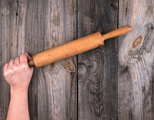 female hands hold old wooden rolling pin