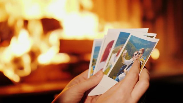 Woman looking at photos from vacation. In the photo, a young couple is resting in the mountains, in the frame you can see only hands on the background of the fireplace