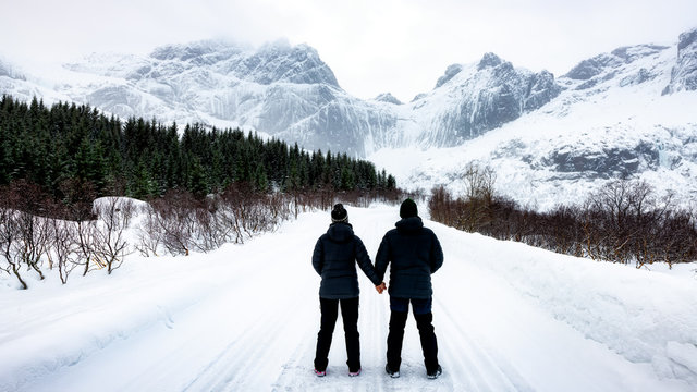 At 68 Degrees North, a couple consider Arctic Winter landscape of Lofoten, Nordland