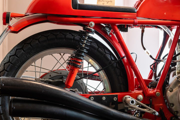 Close up of seat, exhaust, rear wheel and suspension of a red vintage motorcycle