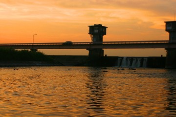 夕日が照らす川面と堰