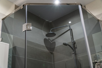 Gray glass shower cabin. The door is closed. Beautiful shower with traces of droplets and lime in bathroom of porcelain stoneware. Gray shades