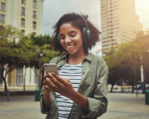 Young woman using mobile phone while listening with headphones on her head