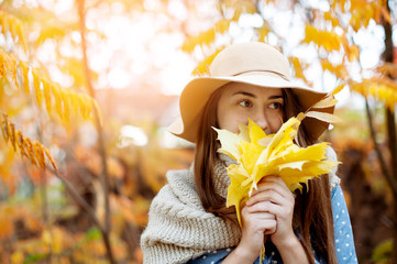 Beautiful young woman holding a bunch of autumn leaves