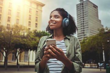 Outdoor portrait of woman listening to music using mobile phone