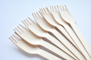 Wooden disposable forks on white background, eco friendly, natural, zero waste product, close up view, selective focus.