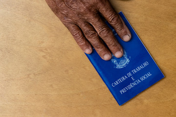 hands of black senior man holding work book, Brazilian social security document