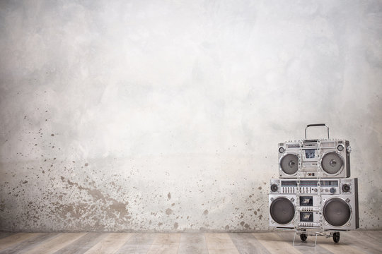 Retro old design ghetto blaster boombox stereo radio cassette tape recorders from circa 1980s on handcart front concrete wall background. Rap and Hip Hop music concept. Vintage style filtered photo