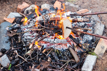 Marshmallows and slice of bread on a stick over bonfire