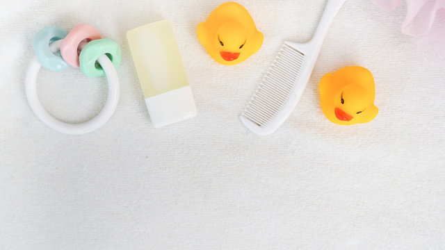 Flat laybaby bathroom stuff. White baby soap bar, pinksponge, shampoo bottle, yellow rubber duck and white hair brush. child white towel. Free space for text, mock-up