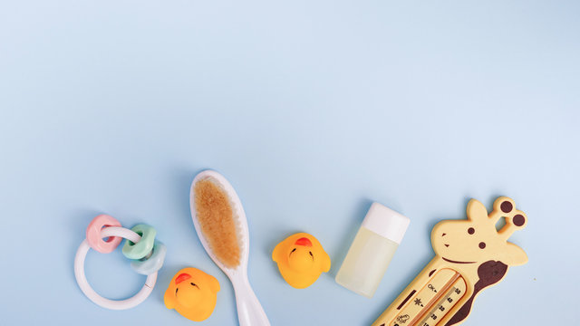 Baby bath products on blue background with copy space. flat lay soap bar, yellow rubber duck and liquid soap, toy