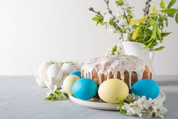 Easter cake, colored eggs on the event family table with cherry blossoms flowers. Space for text.