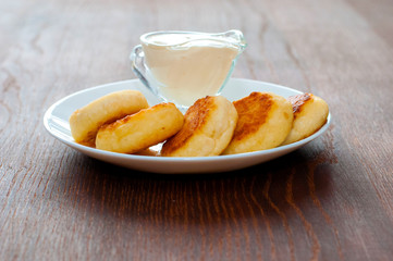 Fried cheesecakes with sour cream side view. For cafe or restaurant menu design.