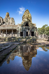 Relections of the towers and beautiful face sculptures at the famous Bayon temple in the Angkor Thom temple complex, Siem Reap, Cambodia