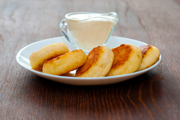Fried cheesecakes with sour cream side view. For cafe or restaurant menu design.
