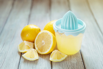 Freshly squeezed lemon juice with juicer on wooden table, copy space