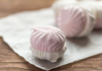 Fototapeta na wymiar delicious dessert, delicate white and pink marshmallow on white paper on wooden background,