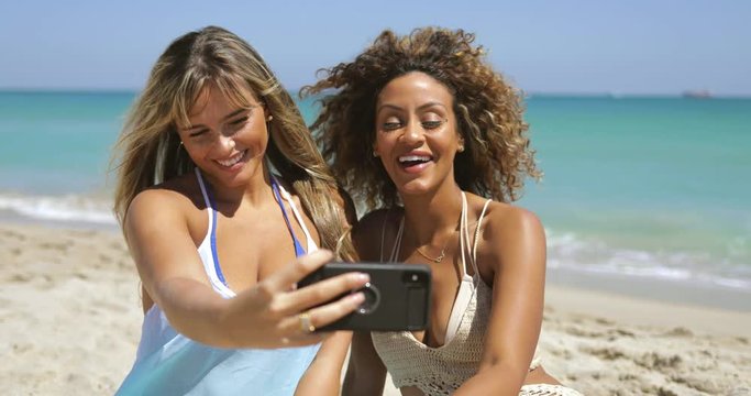 Playful women posing for selfie on beach