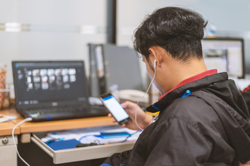 business man working and play smart phone in office with soft-focus and over light in the background