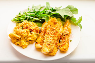 Zucchini sticks in breadcrumbs with hummus sauce and arugula. Horizontal.Close-up.