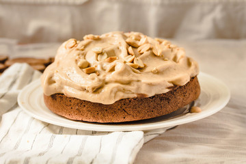 Chocolate cake with banana mousse cream icing with peanuts. On white linen tablecloth background. Diet detox food and vegan food concept.