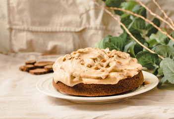 Chocolate cake with banana mousse cream icing with peanuts. On white linen tablecloth background. Diet detox food and vegan food concept.