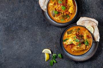 INDIAN FOOD. Traditional KERALA FISH CURRY with naan bread, gray plate, black background 