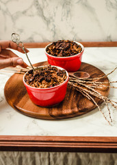 Cherry crumble with chocolate granola served served in portioned red plates..The process of eating. In the hands of a young woman.