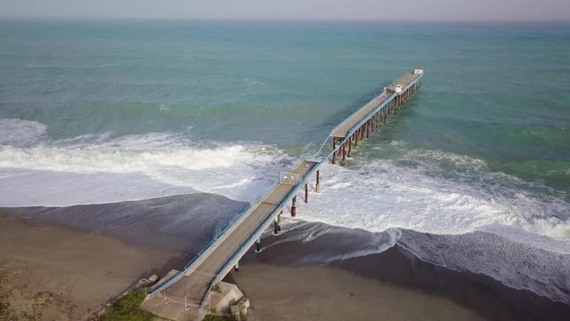 Pontile industriale sull' Oceano distrutto e crollato dalle onde tempestose.
