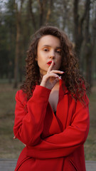 Fototapeta na wymiar Glamorous woman wearing red outfit and matching red lip gloss. Portrait in the park