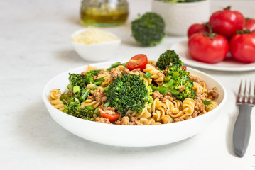 Pasta with meat sauce, cherry tomatoes and broccoli. Mediterranean cuisine with pasta ingredients - olive oil, broccoli and tomatoes.