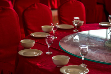 Closeup of table setup with formal dinning placement of plates and liquor glasses. Tables prepared for party or formal celebration of wedding